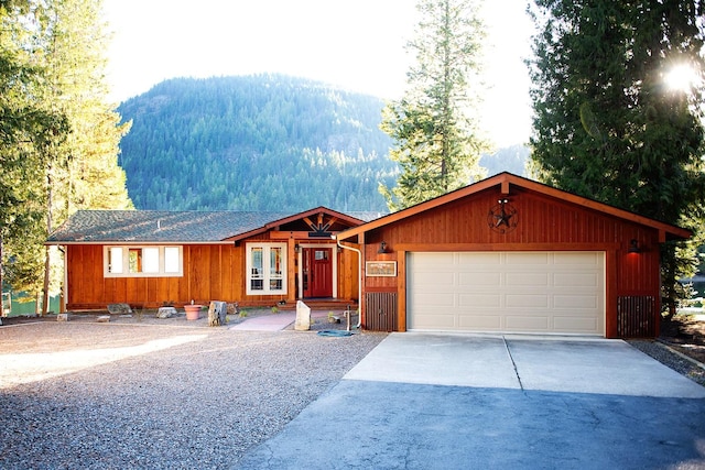 view of front of house with concrete driveway, a garage, and a view of trees