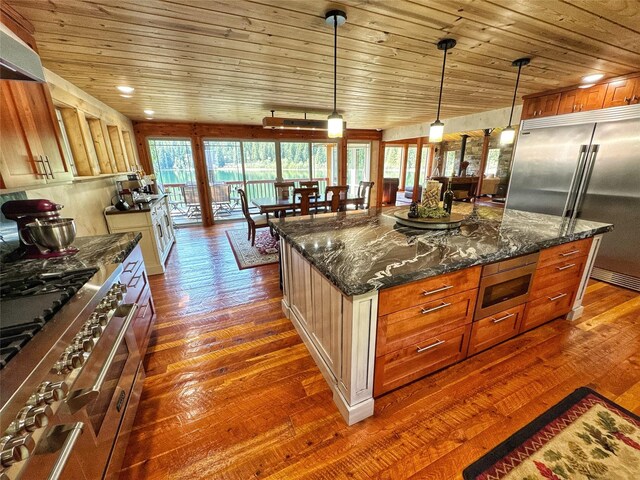 kitchen featuring a sink, brown cabinetry, wall chimney exhaust hood, double oven range, and wood ceiling