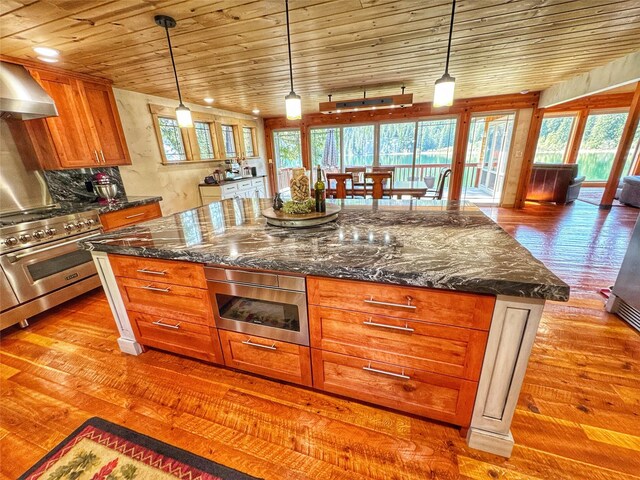 kitchen featuring light wood-style flooring, a sink, dark stone countertops, brown cabinetry, and backsplash