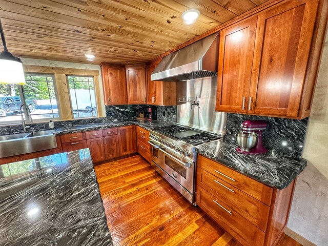 kitchen with a sink, brown cabinetry, light wood-style floors, built in appliances, and wooden ceiling