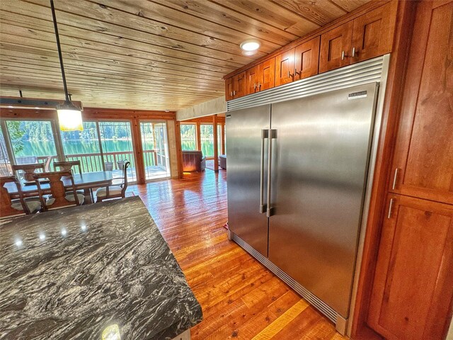 kitchen featuring a sink, brown cabinetry, light wood-type flooring, wood ceiling, and stainless steel built in fridge