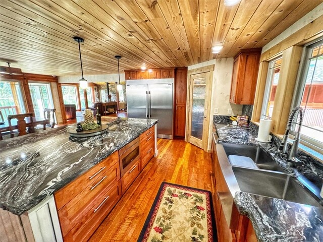kitchen with built in appliances, a healthy amount of sunlight, light wood-style flooring, and wood ceiling