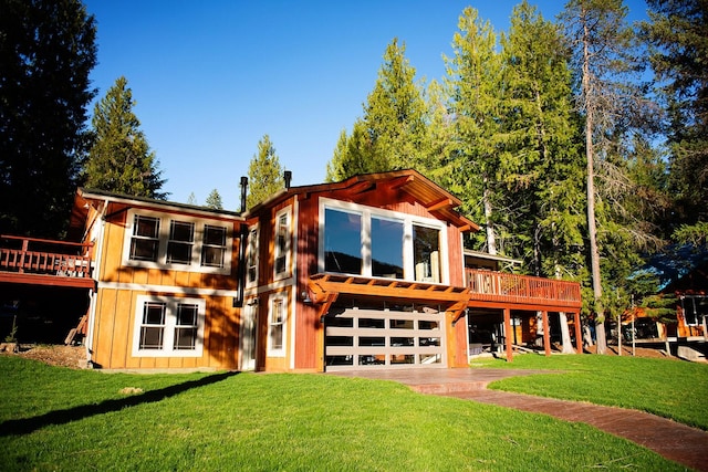 back of house featuring a yard, driveway, a deck, and a garage