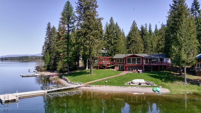 view of dock with a forest view, a pergola, a lawn, and a deck with water view