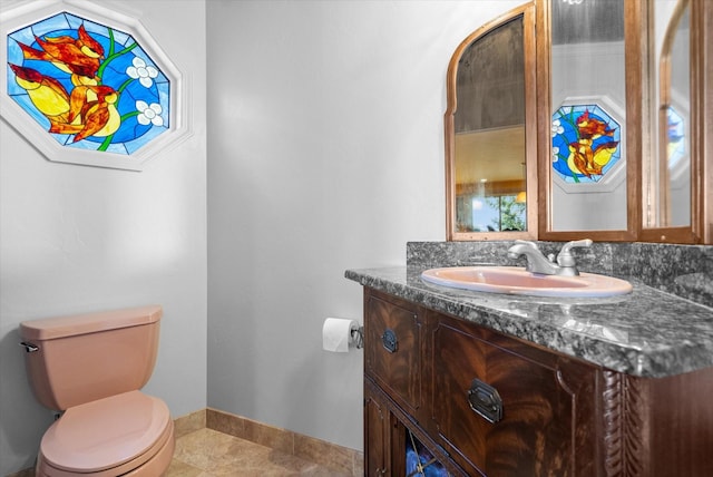 bathroom with vanity, toilet, baseboards, and tile patterned flooring