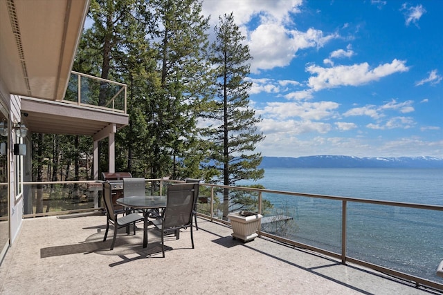 balcony with a water and mountain view and outdoor dining space