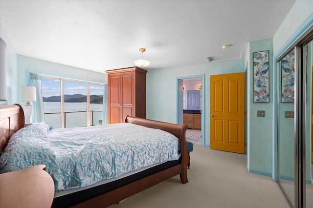 bedroom featuring a water view, light carpet, and attic access