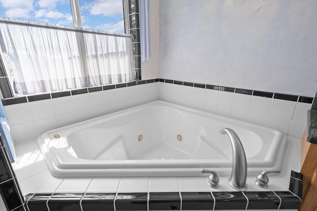 full bath featuring a tub with jets and a textured wall