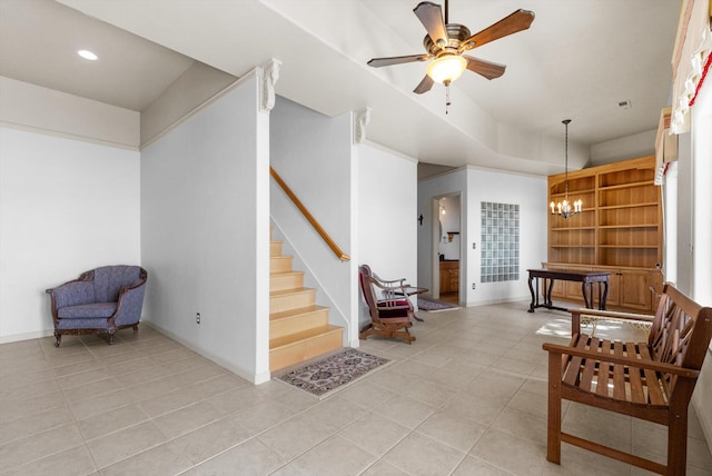 living area featuring light tile patterned floors, stairs, baseboards, and ceiling fan with notable chandelier