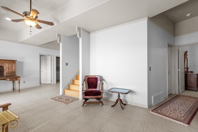 living area featuring light tile patterned floors, visible vents, baseboards, and a ceiling fan