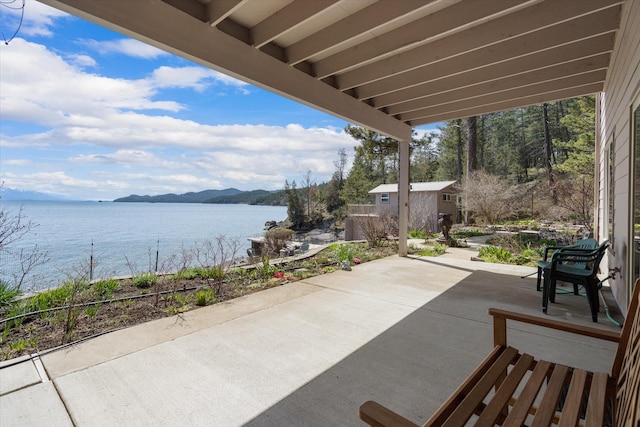 view of patio featuring a water and mountain view and an outbuilding