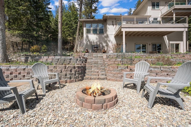 view of patio with stairs, a fire pit, and a balcony
