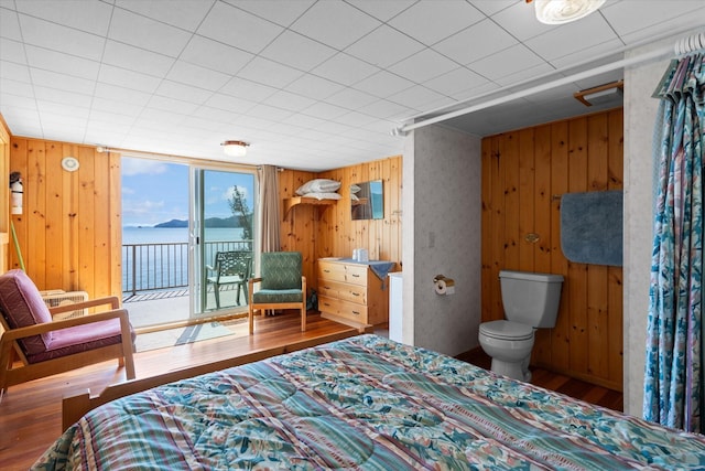 bedroom featuring wooden walls, wood finished floors, and access to exterior