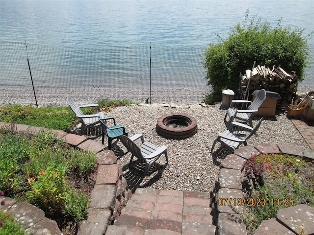 view of patio with a water view, a fire pit, and fence