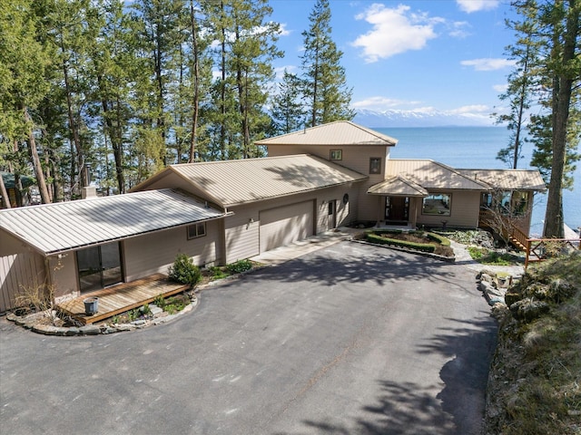 view of front of home featuring an attached garage, driveway, metal roof, and a water view