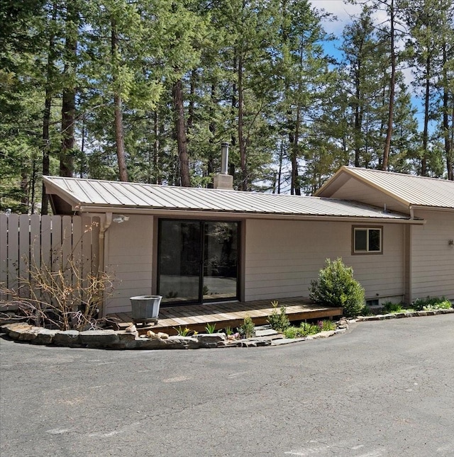 view of front of house with a wooden deck, a chimney, metal roof, and a standing seam roof
