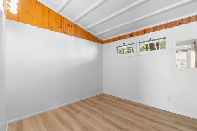 unfurnished room featuring vaulted ceiling, baseboards, and light wood-style floors