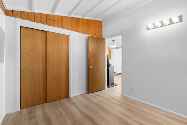 unfurnished bedroom with light wood-style flooring, a closet, and baseboards