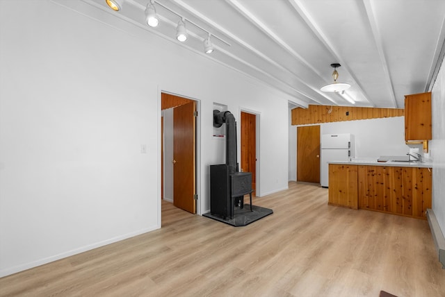 kitchen with freestanding refrigerator, brown cabinets, a wood stove, and light wood finished floors