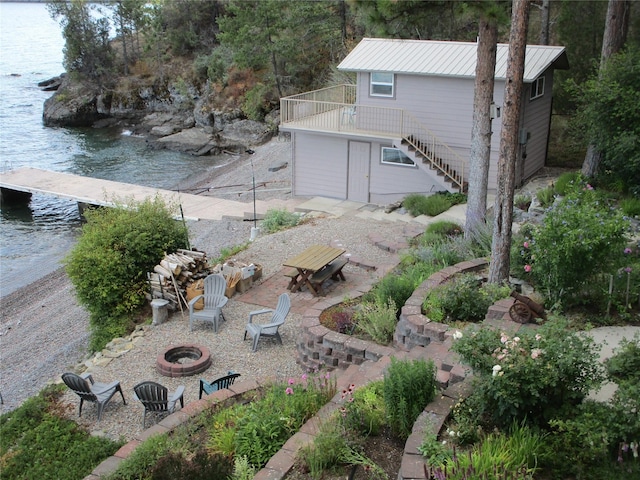 view of yard with a patio, a water view, an outdoor fire pit, a boat dock, and stairs