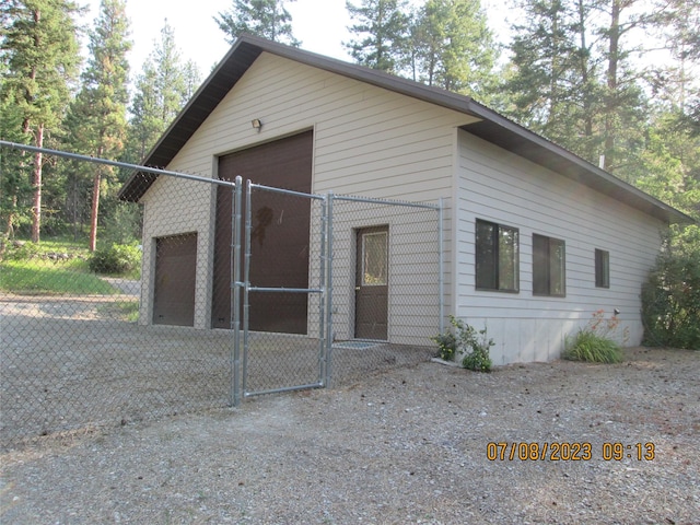 view of front of property with a gate, a detached garage, and fence