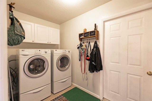 clothes washing area featuring washing machine and dryer, cabinet space, and baseboards