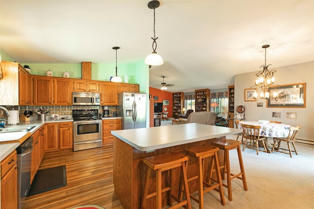 kitchen featuring a sink, ceiling fan with notable chandelier, light countertops, tasteful backsplash, and appliances with stainless steel finishes