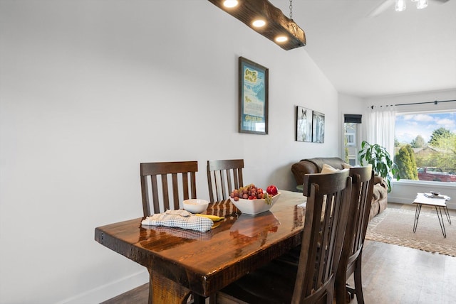 dining area with lofted ceiling, baseboards, and wood finished floors