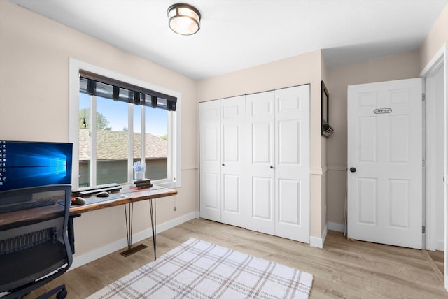 office area with baseboards, light wood-type flooring, and visible vents