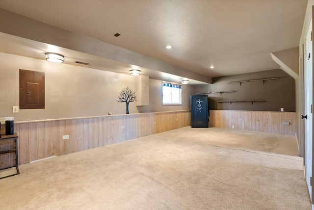 basement with electric panel, carpet flooring, wooden walls, and wainscoting