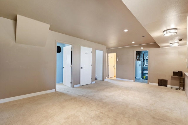 empty room with baseboards, recessed lighting, light colored carpet, and gas water heater