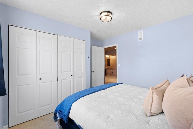 carpeted bedroom with a textured ceiling, a closet, and visible vents
