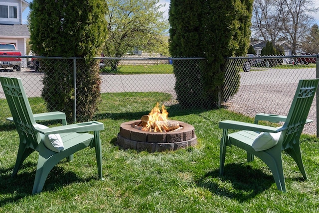 view of home's community with a fire pit, fence, and a lawn