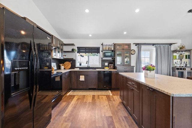 kitchen featuring light wood finished floors, a sink, open shelves, black appliances, and tasteful backsplash