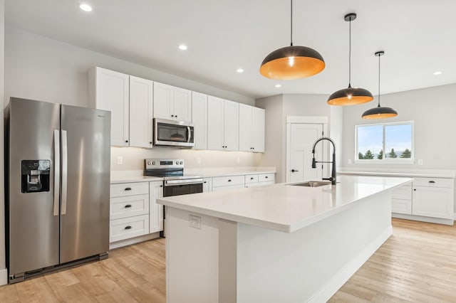 kitchen with light wood-type flooring, light countertops, appliances with stainless steel finishes, and a sink