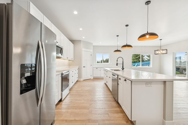kitchen with light wood-type flooring, light countertops, appliances with stainless steel finishes, and a sink