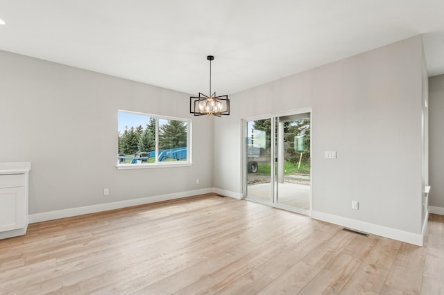 unfurnished dining area with light wood-type flooring, baseboards, a chandelier, and visible vents