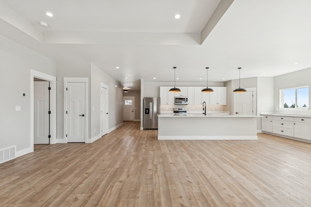 unfurnished living room with light wood-style flooring, recessed lighting, baseboards, visible vents, and a raised ceiling