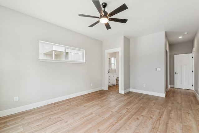unfurnished bedroom featuring connected bathroom, light wood-type flooring, baseboards, and a ceiling fan