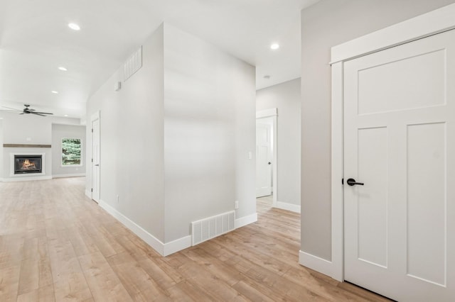 hallway featuring light wood-style floors, visible vents, baseboards, and recessed lighting