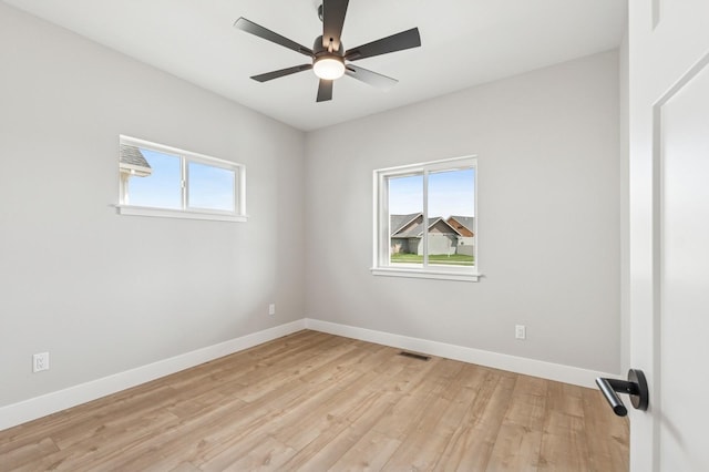 spare room with light wood finished floors, a wealth of natural light, visible vents, and baseboards