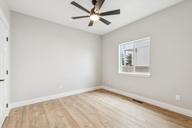 spare room with a ceiling fan, visible vents, wood finished floors, and baseboards