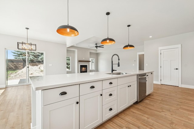 kitchen featuring white cabinetry, light wood-style floors, a sink, and dishwasher