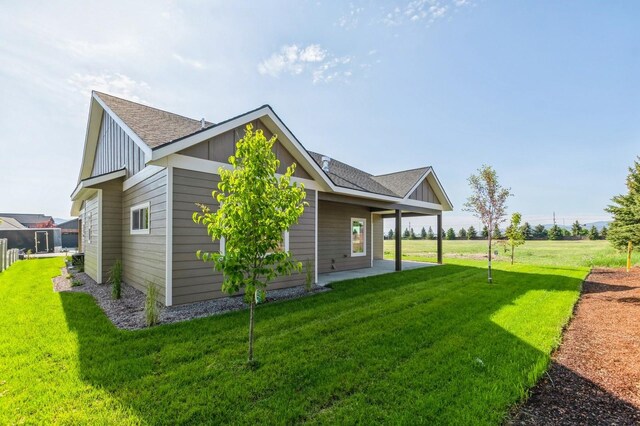268 Landing Ln, Kalispell, MT 59901 - view of home's exterior with a lawn, a patio, roof with shingles, and board and batten siding