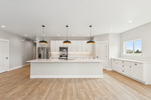 kitchen with light wood-style floors, light countertops, appliances with stainless steel finishes, and a sink