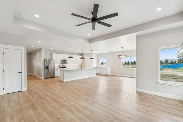 unfurnished living room featuring recessed lighting, light wood-type flooring, ceiling fan, and a sink
