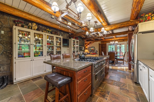 420 Deer Creek Rd, Lakeside, MT 59922 - kitchen with a chandelier, stainless steel appliances, stone tile floors, dark stone countertops, and a kitchen island