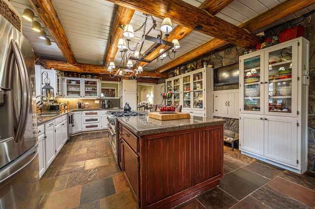 420 Deer Creek Rd, Lakeside, MT 59922 - kitchen featuring appliances with stainless steel finishes, stone tile floors, a center island, glass insert cabinets, and a wooden ceiling with exposed beams