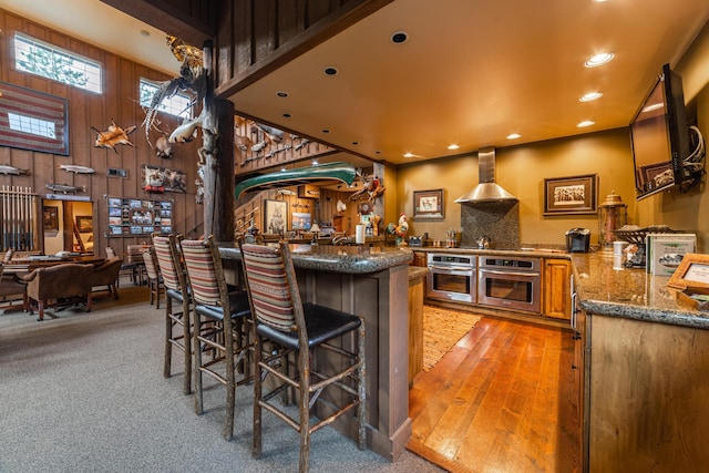 420 Deer Creek Rd, Lakeside, MT 59922 - kitchen featuring oven, wall chimney range hood, dark stone countertops, a peninsula, and recessed lighting