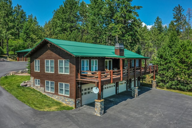 420 Deer Creek Rd, Lakeside, MT 59922 - view of front facade featuring stone siding, a chimney, a garage, and asphalt driveway